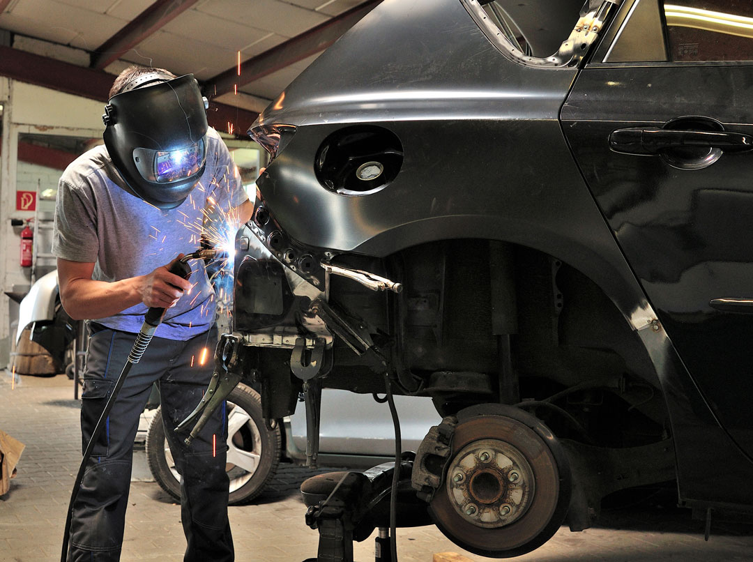 Technician MIG-welding a body panel on a vehicle in the Vorenza Auto Repair shop