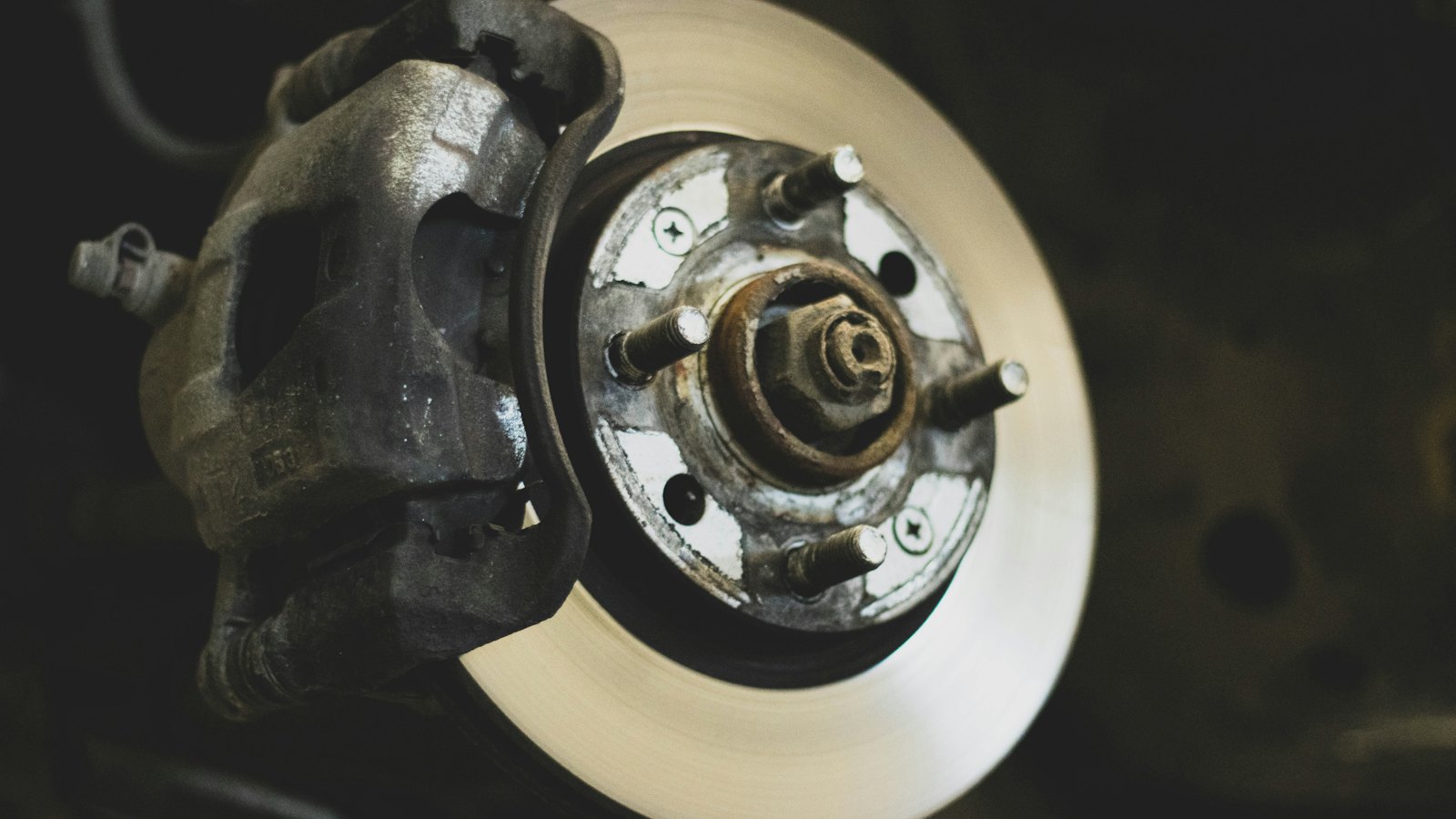 Brake rotor and caliper on a car with the wheel removed, ready for pad and rotor measurements during a brake inspection in Derry, NH