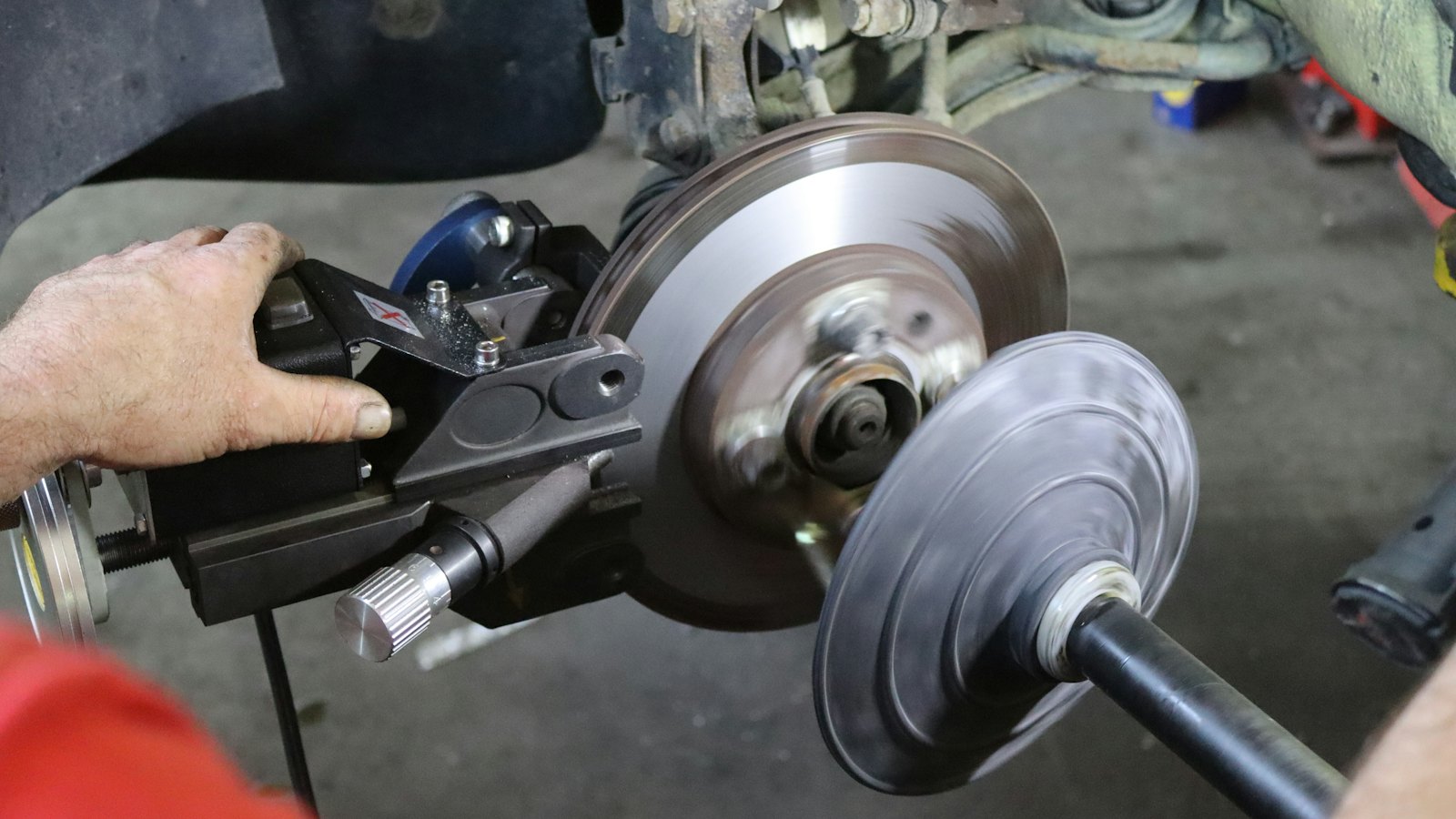 Technician resurfacing a brake rotor with an on-car brake lathe to remove the grooves and rust that make brakes noisy