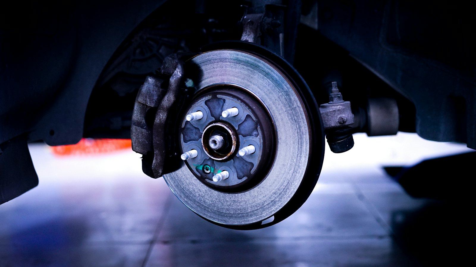 Brake rotor and caliper on a car with the wheel removed, where the cause of brakes squeaking or grinding is usually found