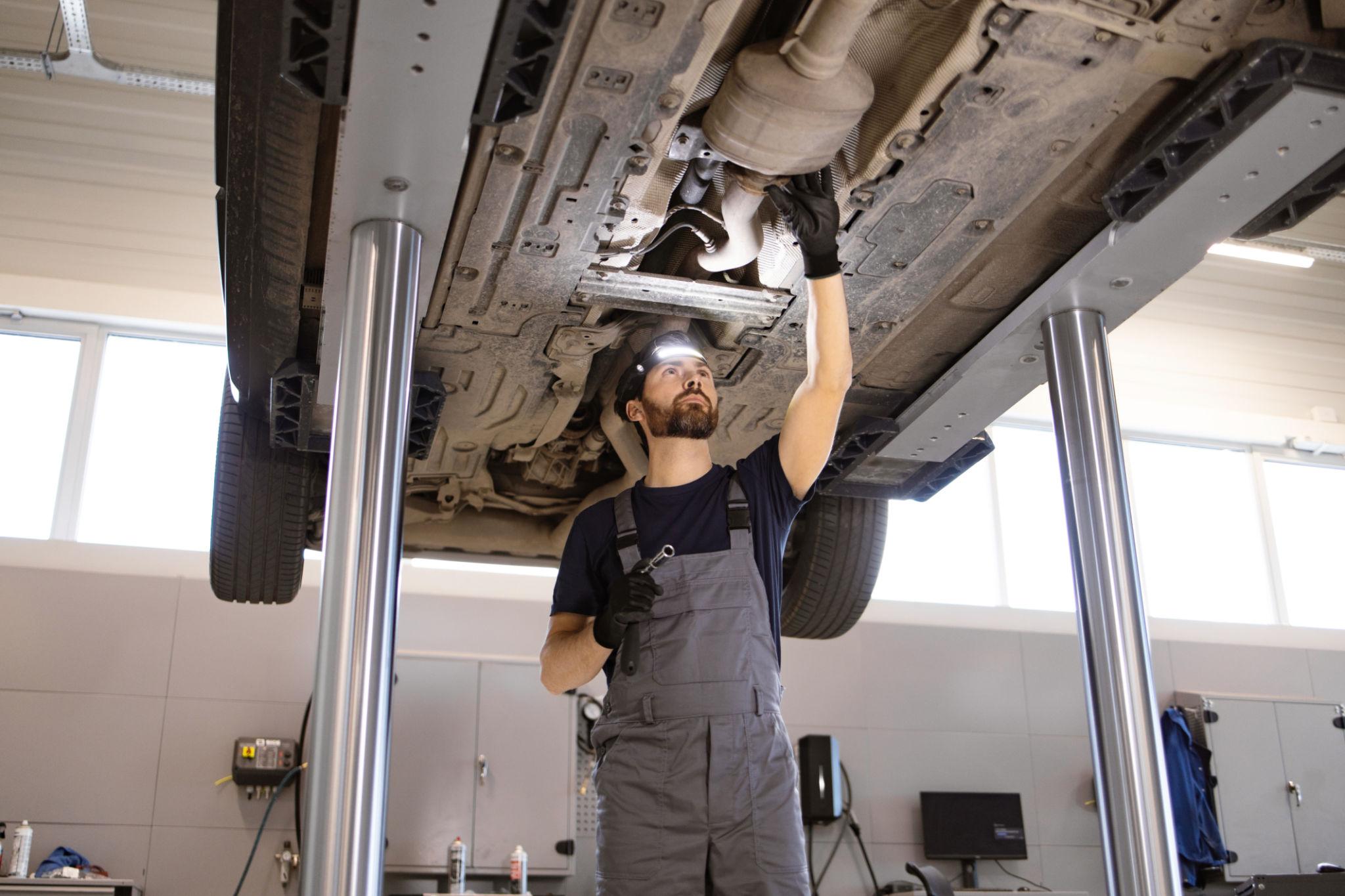 ASE-certified technician inspecting a vehicle's undercarriage on a lift at an independent auto repair shop in Derry, NH