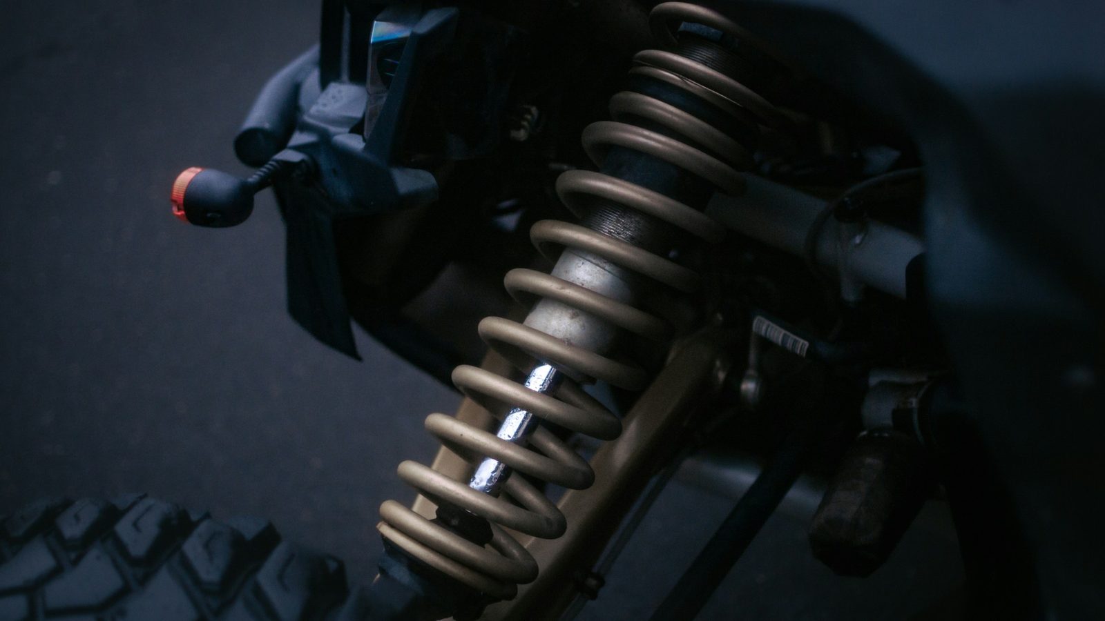 Close-up of a coil spring and shock absorber on a vehicle raised for suspension repair in Derry, NH