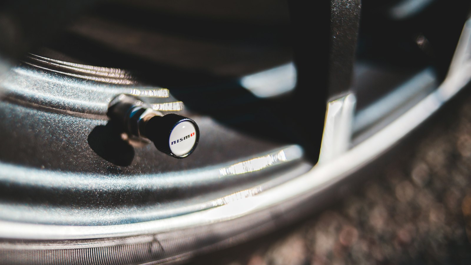 Close-up of a capped tire valve stem on an alloy wheel, where corrosion from road salt can cause slow leaks and TPMS sensor problems