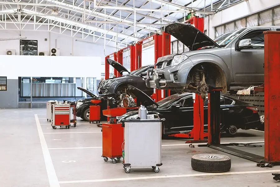 Used cars raised on lifts with hoods open for a pre-purchase car inspection at Vorenza Auto Repair in Derry, NH